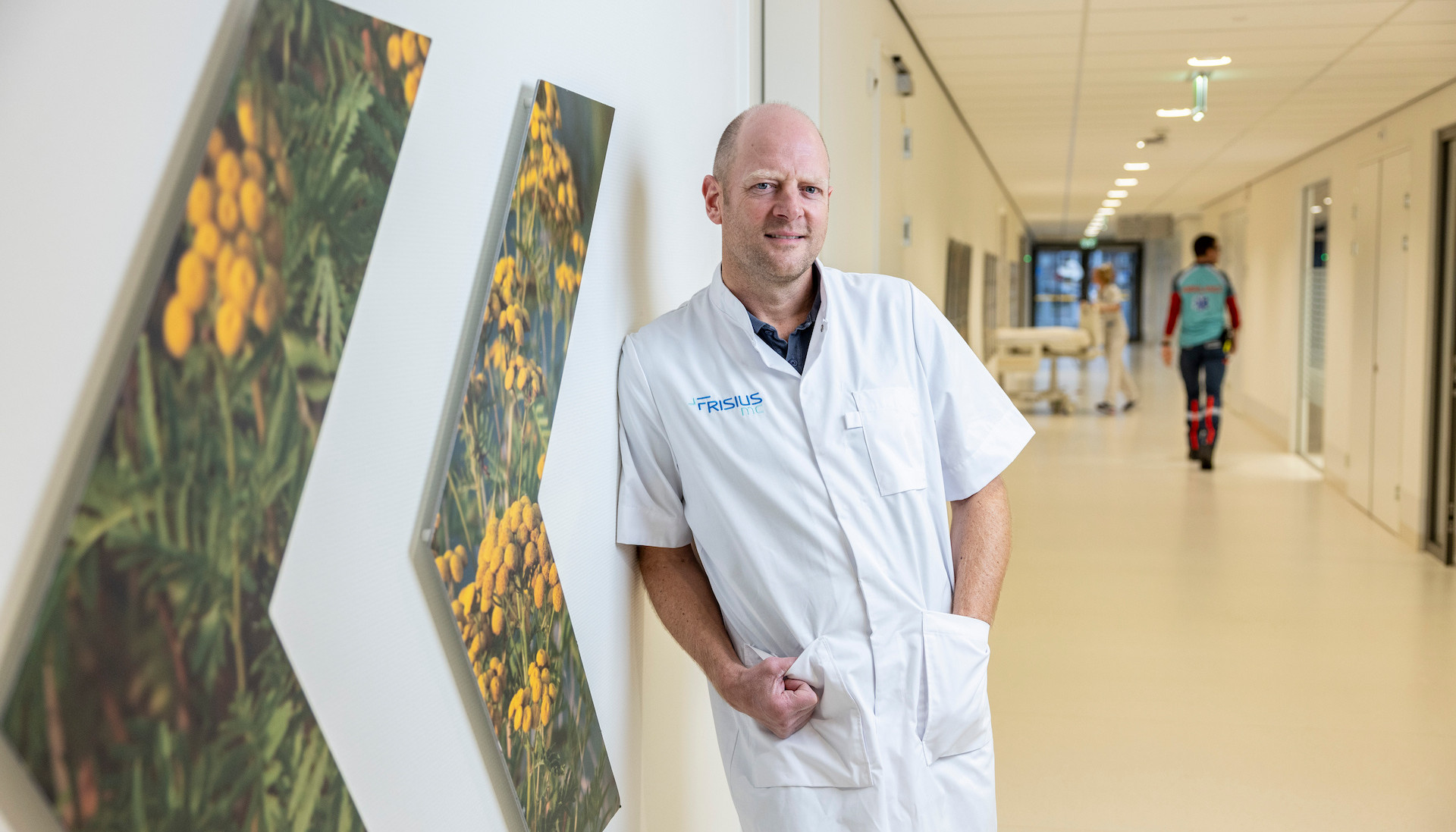 Een arts in een ziekenhuisgang leunt tegen de muur.